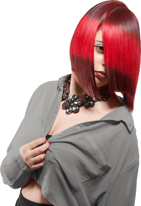 A woman with vibrant red and black hair, wearing a gray shirt and a chunky black necklace, partially covers her face with her hair, looking at the camera with a subtle expression.