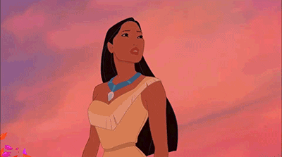 Animated image of pocahontas, a character from disney, standing with a wind-blown appearance against a pink and orange sky background.