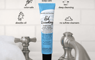 A tube of bumble and bumble bb. sunday shampoo stands between two metal faucets over a subway tile backsplash, highlighted by annotations about its features: color-safe, absorbs oil, deep cleansing, no sulfate cleansers.